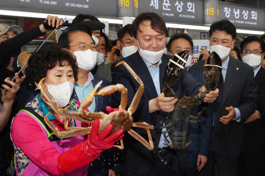 제20대 대통령선거 예비후보로 등록한 윤석열(가운데) 전 검찰총장이 27일 오후 부산 중구 자갈치시장을 방문해 랍스터를 들어 올리고 있다.연합뉴스·부산사진공동취재단